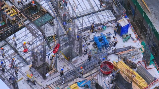 Aerial view of a busy construction site with workers assembling rebar and formwork for a building