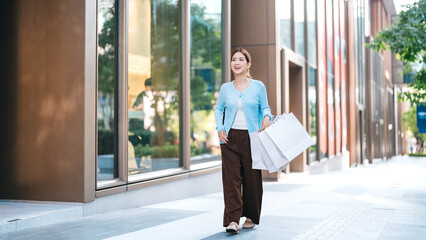 Fototapeta premium Young adult asian woman holding shopping bags in city shopper duty free