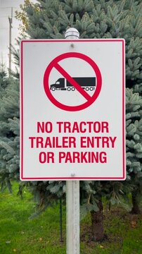 "NO TRACTOR TRAILER ENTRY OF PARKING" sign with a caricature of a truck with a red circle and line drawn across, banning the entry of commercial transport. 