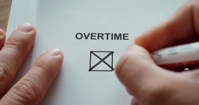 Close-up of a person marking an overtime checkbox on a document, representing extra working hours, workload, employment and workplace administration.
