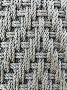 Close up of thick woven grey rope pattern texture. Detailed macro background of heavy duty braided fiber mesh. Primer plano de textura de cuerda trenzada gris con patr&oacute;n geom&eacute;trico. No AI.