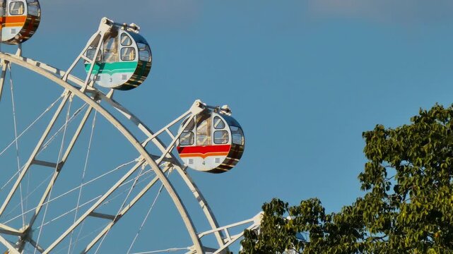 Static Shot of a Rotating Ferris Wheel in an Amusement Park Landscape
