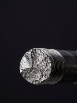 Macro Close-up of Metal Fatigue Fracture Surface on Threaded Steel Bolt Rod Showing Brittle Failure Pattern Isolated on Black Background for Engineering Failure Analysis and Industrial Material Testin