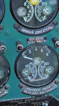 Close up of Mi-24 helicopter instrumentation with worn paint, Cyrillic text, and analog dials measuring pressure and temperature. Mechanical switches and labels indicate flight controls