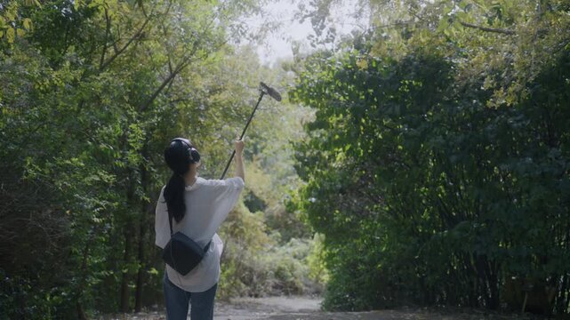 Young Asian Woman Recording Nature Sounds with Boom Microphone in Green Park