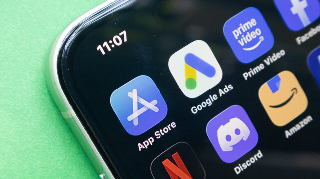 App store google ads and amazon icons on smartphone display against green surface show diverse digital tools.