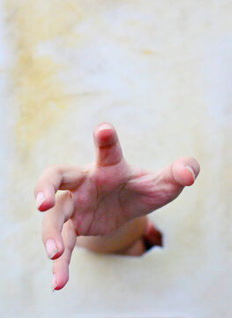 A hand with spread fingers in the broken hole.