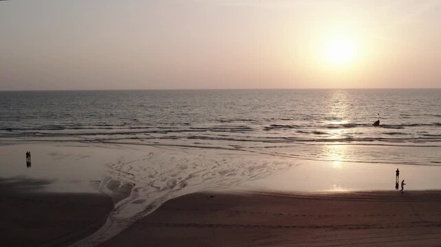 Benaulim beach sunset in goa india with people walking on wet sand