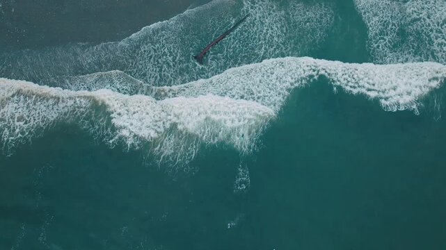 Overhead top down drone footage panning out over ocean waves and whitewater crashing onto Sombrio Beach on Vancouver Island in British Columbia Canada