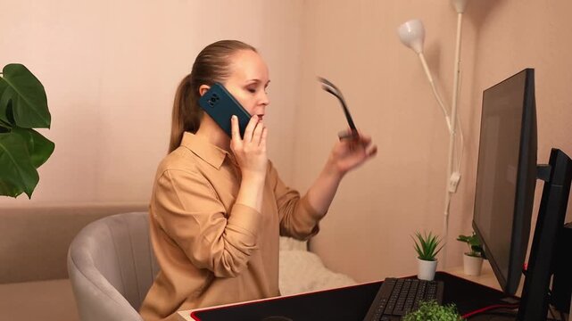 A focused young white woman is working on a computer at her desk. And he's on the phone. She takes the order by phone.