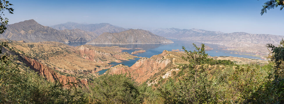 Colorful landscape panorama of Nurek dam lake second highest in world with trees in foreground between Dushanbe and Khatlon, Tajikistan