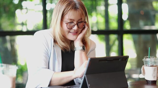 Smiling Businesswoman Working on Tablet in Cafe
