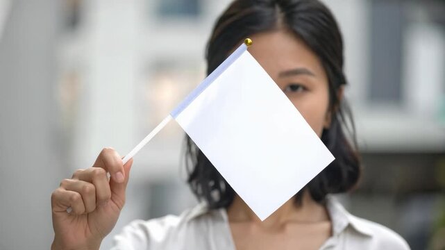 Woman holding blank white flag covering her face in protest