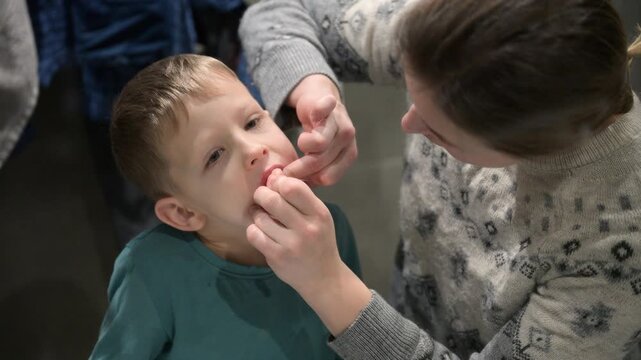 Parent assists toddler with tooth brushing by sink at home, teaching proper oral care habits. Everyday family lifestyle scene focused on childhood hygiene, wellness, and care