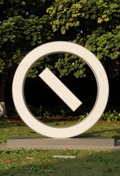 Prohibition and restriction concept, circular no entry sign sculpture in a public park with lush green trees and grass in the background