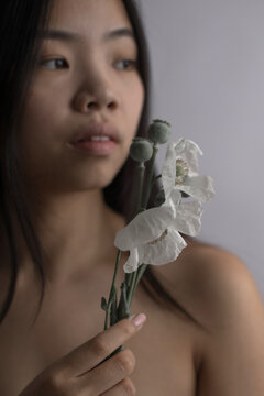 Portrait of Southeast Asian woman holding white flowers with poppy