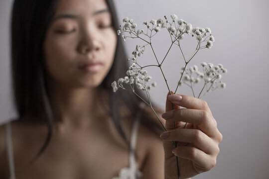 Young Southeast Asian woman holding delicate baby's breath flowers