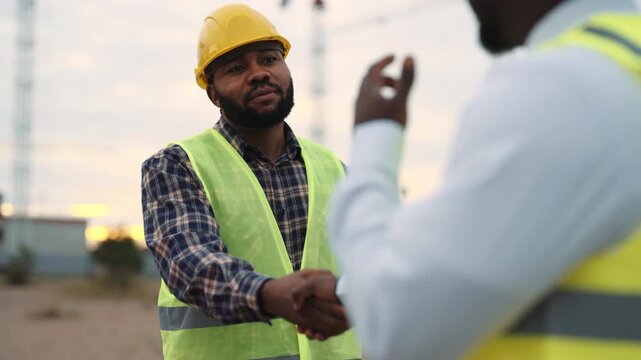 Foreman and builder talking in construction site, make deal in building business . Partners shaking hands, supplier and architect discussing project, contemporary technology and machinery in building