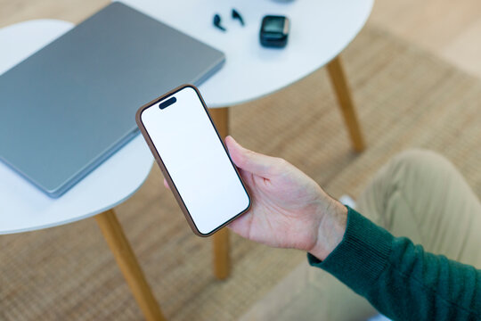 Smartphone held by hand in modern home office setting