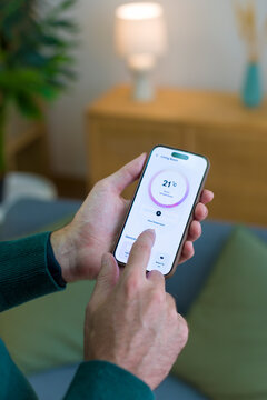 White person adjusting room temperature with smartphone