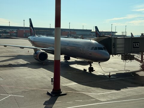 Khimki, Russia - August 22, 2026: American Airlines passenger aircraft stands beside a terminal gate, connected to a boarding bridge on a sunlit airport apron