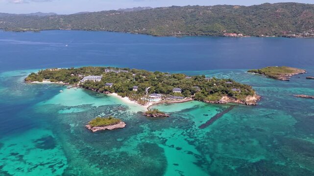Drone footage making a partial orbit around Cayo Levantado revealing turquoise shallows lush vegetation sandy shores and nearby islets in Samana Dominican Republic