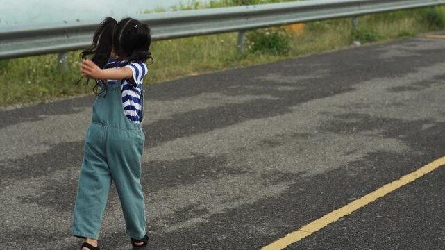 slow motion of preschool child girl walking on a road on mountain in the morning