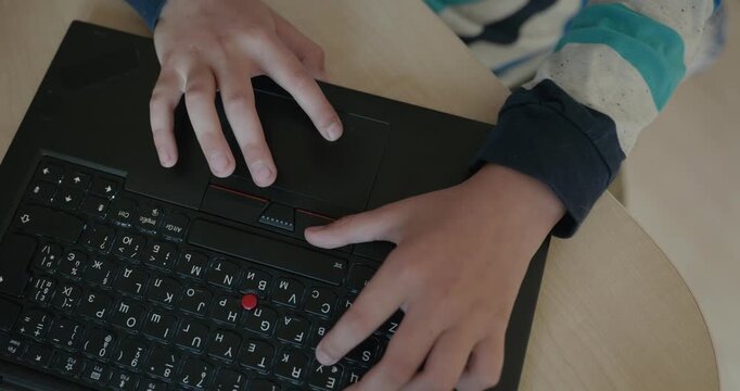 Close-up children's hands typing on laptop computer keyboard. 4K 10-bit