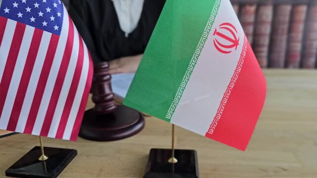 Flags of the United States and Iran displayed in a formal setting with a judge presiding