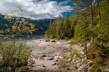 Low water exposes the rocky shore of Lake Eibsee in autumn, ideal for environmental themes © PietFoto