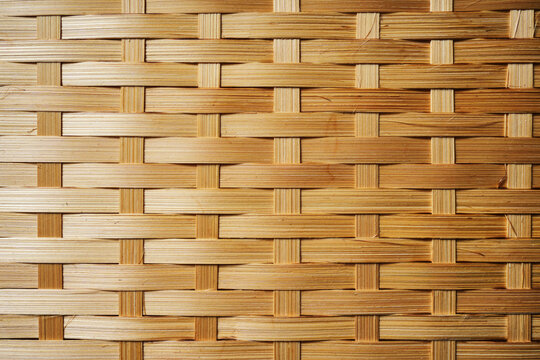 Smooth light brown bamboo strips woven together symmetrical grid pattern natural material.