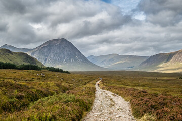 Hikers walking across Rannoch Moor on the West Highland Way trail in Scotland with the Glencoe valley and Buachaille Etive More, Stob Dearg, in the distance © Jon Ingall