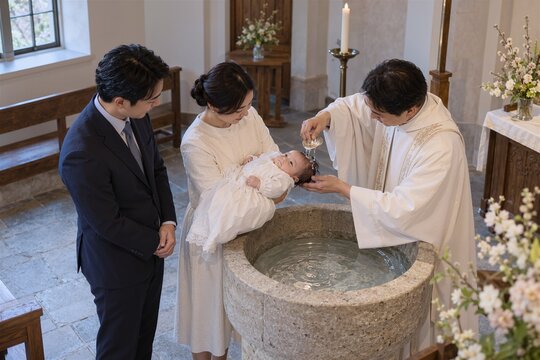 Catholic baptism ceremony with parents standing beside priest pouring water over baby in font. Sacred ritual represents new beginnings and blessings in faith.