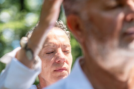 Practitioner with closed eyes performing a focused energy healing gesture during an outdoor guided meditation session, promoting mindfulness, spiritual awareness, inner calm, and emotional balance.