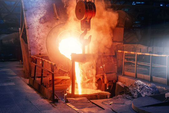 Molten steel pouring from furnace during steelmaking process at metallurgical plant, heavy industry production.