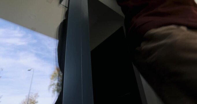 Man opening modern aluminum entrance door with stainless steel handle and exit the building