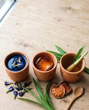 Three Thai herbal drinks, butterfly pea tea, bael fruit and lemongrass tea in terracotta cups