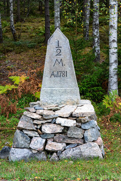 Old historical mile post made from stones near road