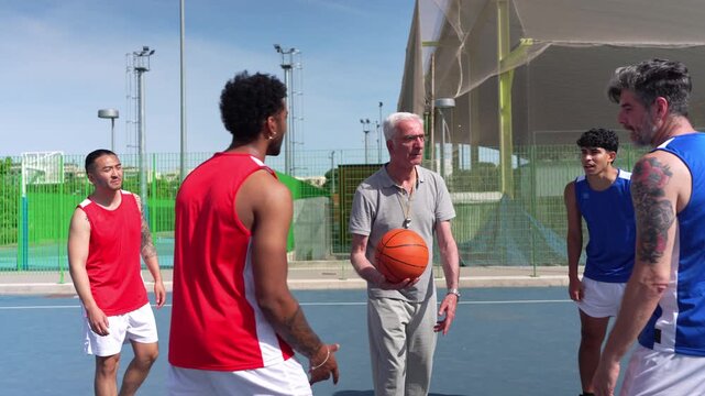Multigenerational men shaking hands before a streetball match. The referee launches the ball for a jump ball between two players