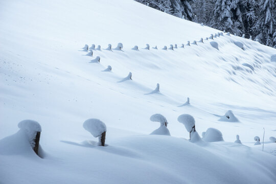Snow covers a wooden fence on a hill in Altenmarkt Austria