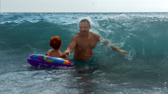Father and son swim in the Black Sea waves