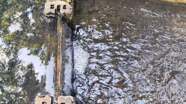 Clear flowing water stream flowing over small weir in nature river ecology background