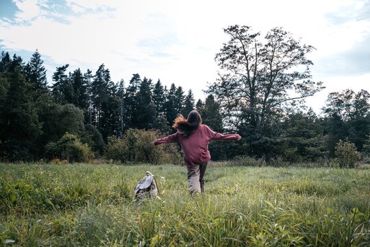 A woman enjoys freedom running outdoors in a green meadow