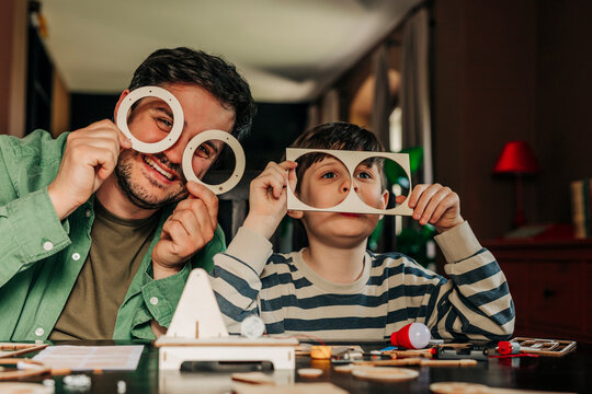 Father and son build a wooden toy kit together at home