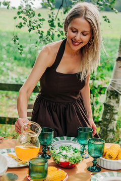 Smiling woman pours juice at an outdoor family dinner table
