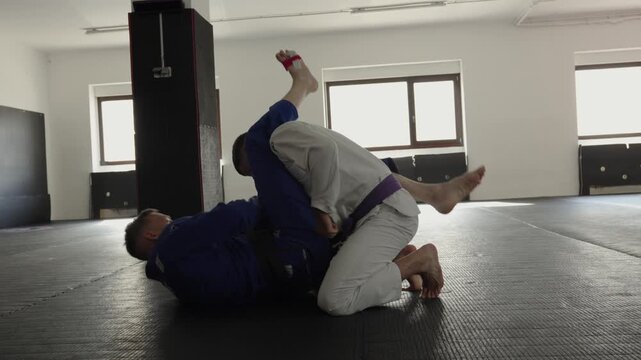 Brazilian jiu-jitsu practitioners applying a lapel collar grip over the bottom practitioner