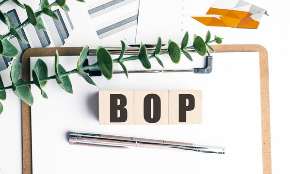 Balance of payments concept with bop letters on wooden blocks, clipboard, pen and financial charts
