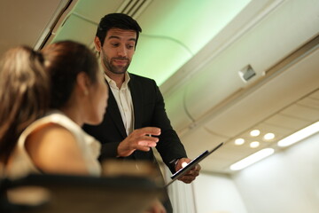 Two passengers in the aircraft cabin turn toward each other mid conversation in the passenger cabin of a plane, good for connection and lifestyle themes, a natural, unposed moment in the air © ultramansk