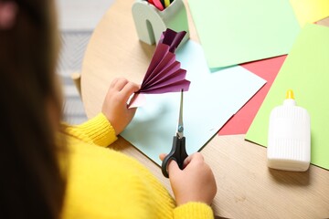 Little girl making craft with paper and scissors at table indoors, closeup. Child creativity and art © New Africa