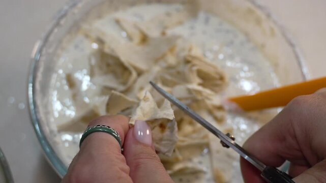 Chef preparing gourmet pita pieces for creamy mixture. Overhead close-up shot.